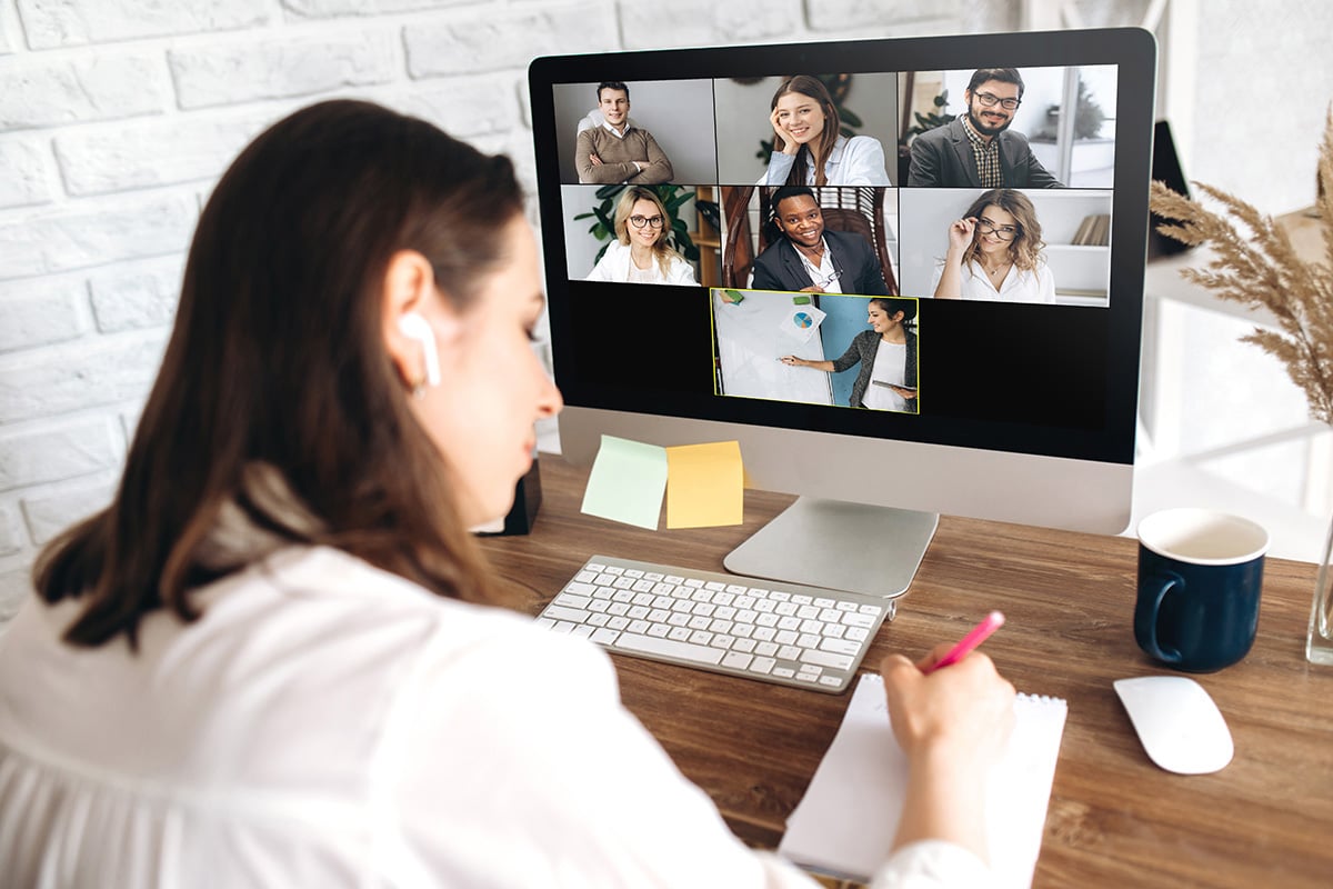 A woman taking notes during a virtual meeting