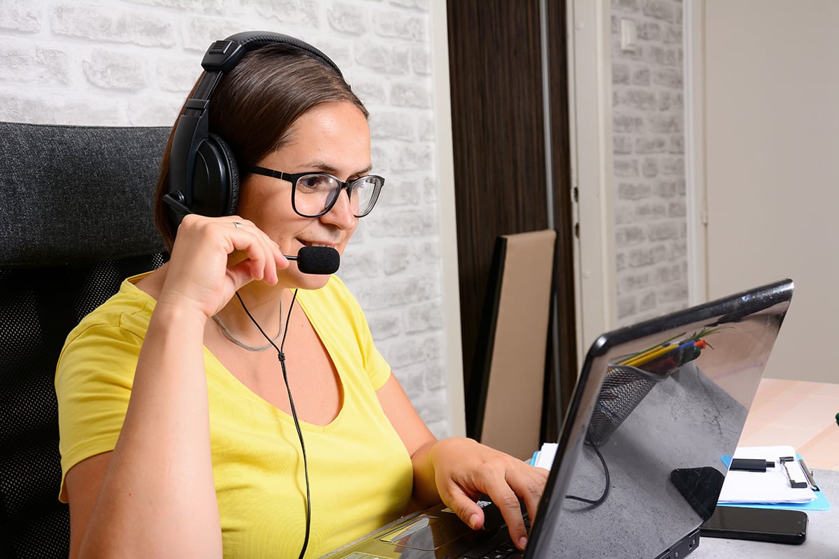 Woman with headset talking to her laptop