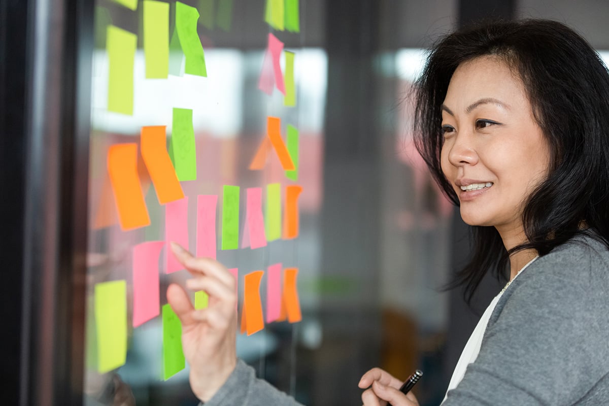 How to Be Selfish With Your Time, Without Being a Jerk: Woman looking at post-it notes on a glass wall