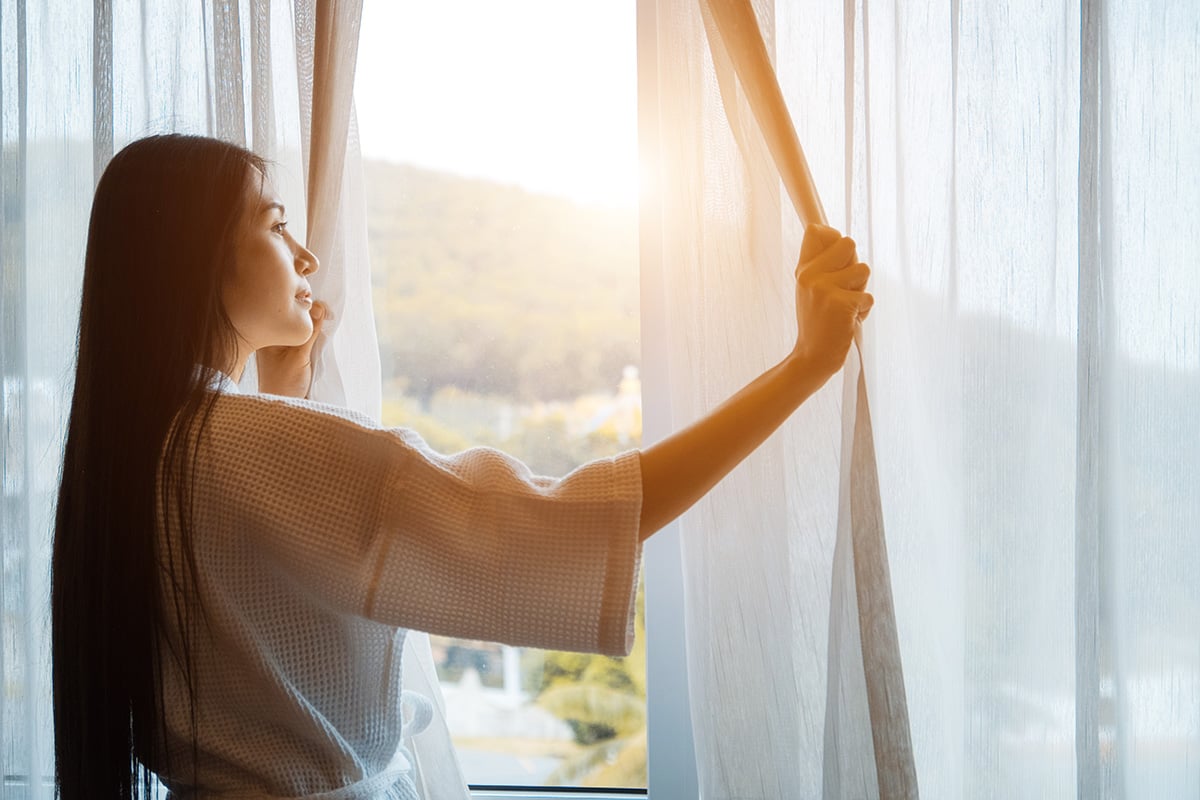 Woman looking outside her window in the morning