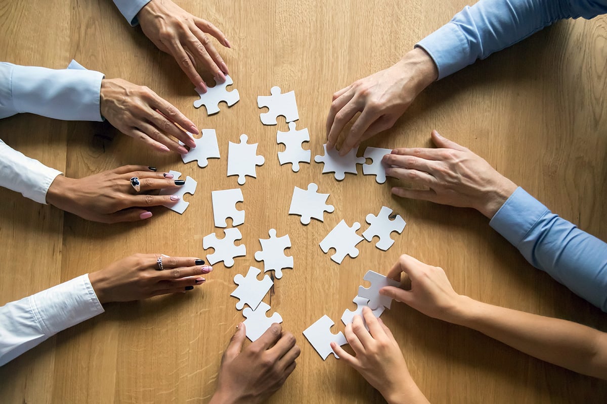 Several hands piecing together a puzzle