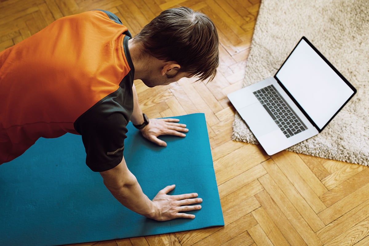 A man doing push-ups in front of his laptop