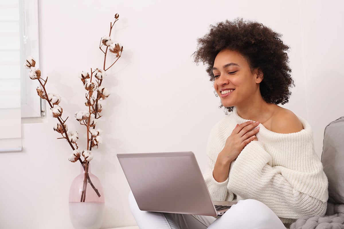 A woman looking at her laptop with a smile on her face