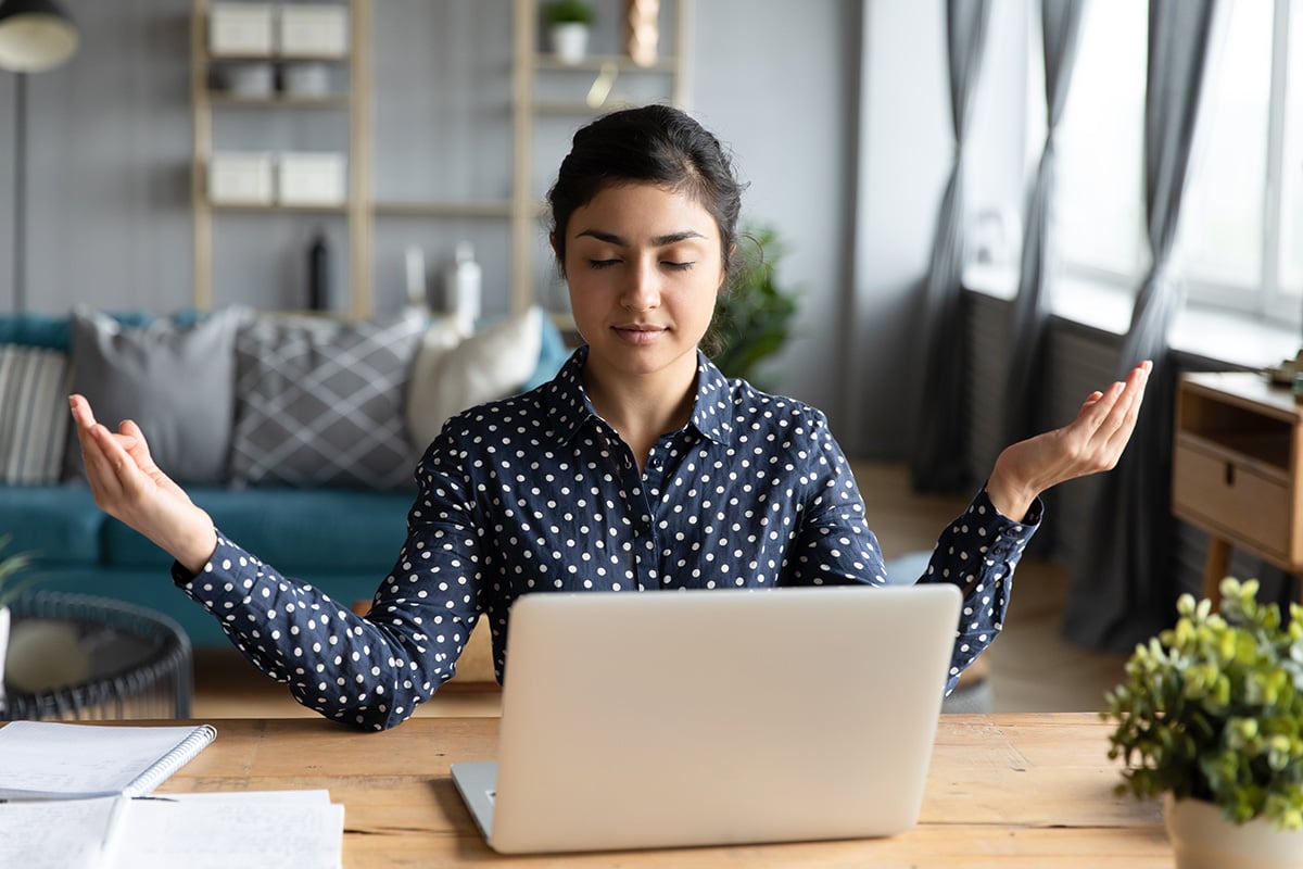 A woman meditating in front of her laptop